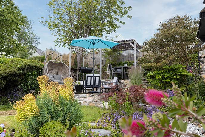 The idyllic garden at dog-friendly Chou Cottage in South Devon complete with covered seating and blooming flowers