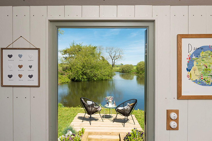 Looking out the door of dog-friendly property Hayley's Hut at the garden chairs and lake
