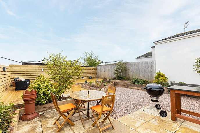 The patio area of dog-friendly Nelson's Retreat in South Devon, complete with decked seating and a BBQ