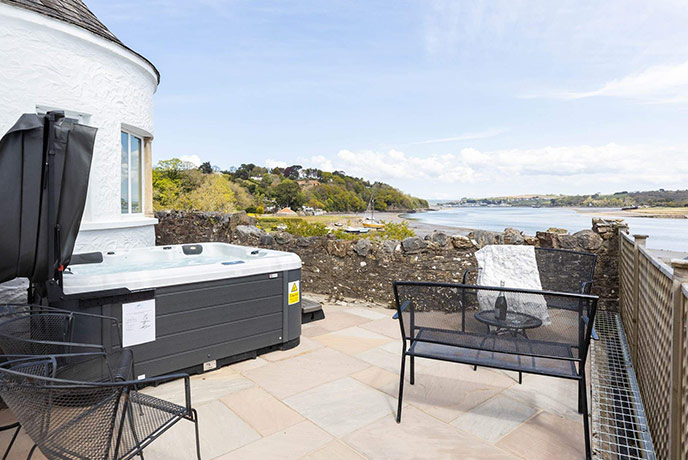 The outdoor patio complete with waterside views and a hot tub at dog-friendly Devon property The Old Kiln