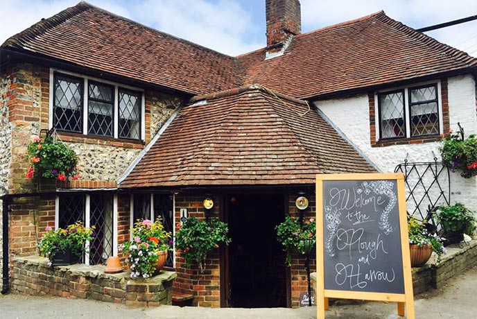 The classic exterior of The Plough and Harrow with its Tudor windows and rose bushes