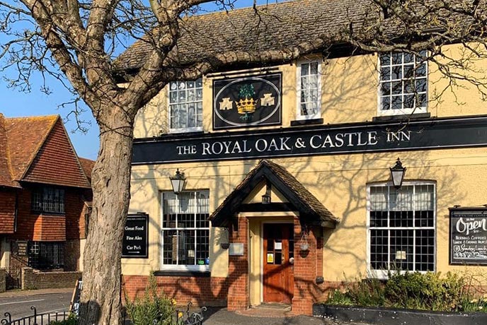 The soft  yellow exterior of The Royal Oak and Castle with the oak tree standing in front