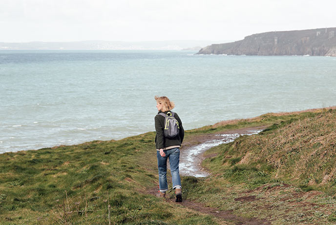 Emma Scattergood walking along the coast path on the cliffs above the sea in Cornwall