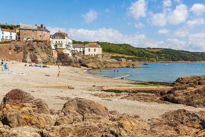 Looking over the rocks and up the beach at pretty cottages on Cawsand beach on the Rame Peninsula
