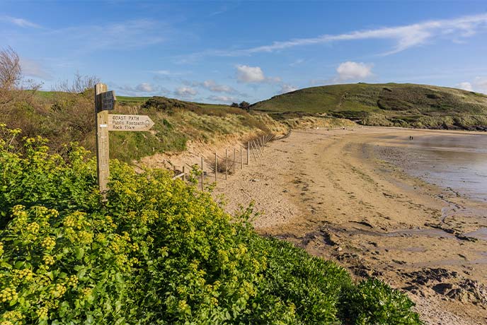 A coast path sign next to the golden sands of Daymer Bay in North Cornwall