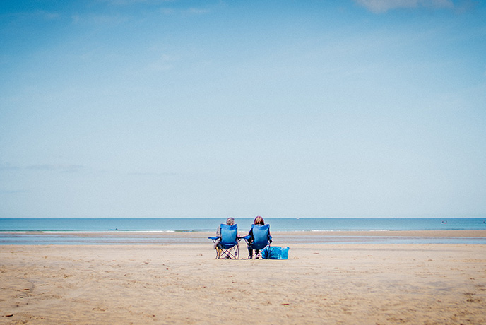 Two people sitting in chairs on Gwithian beach in Cornwall