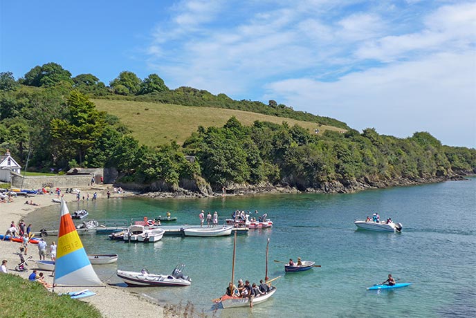 Lots of boats in the water and people on the beach at Helford Passage in Cornwall