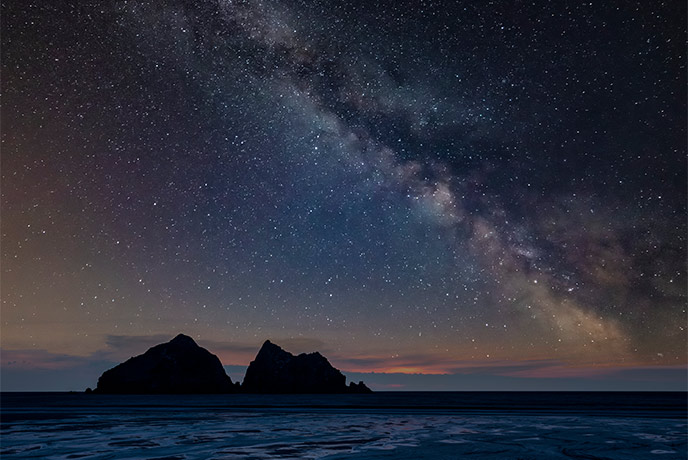 Gull Rocks at Holywell Bay with the starry night sky behind