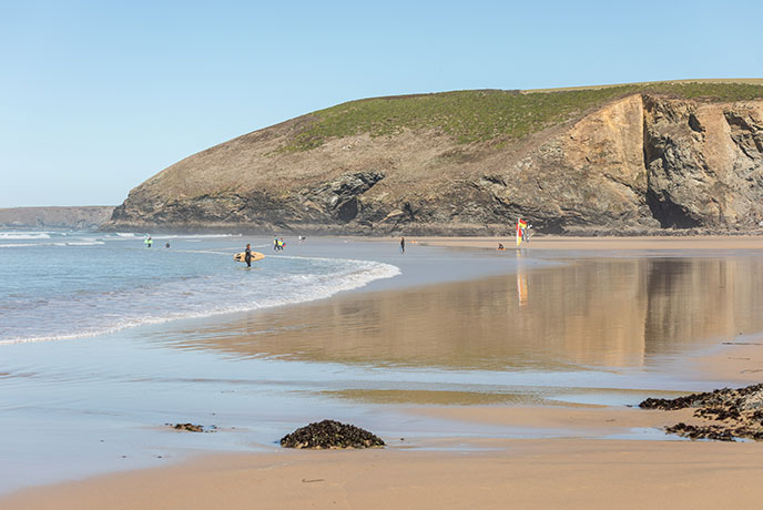 Looking across the sandy beach at Mawgan Porth at the surf and cliffs