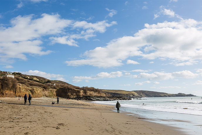 People walking along the golden sandy beach at Perranuthnoe in West Cornwall