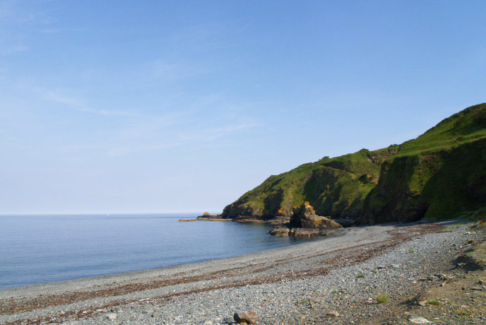 Looking across the pebbly beach at Porthkerris towards the cliffs