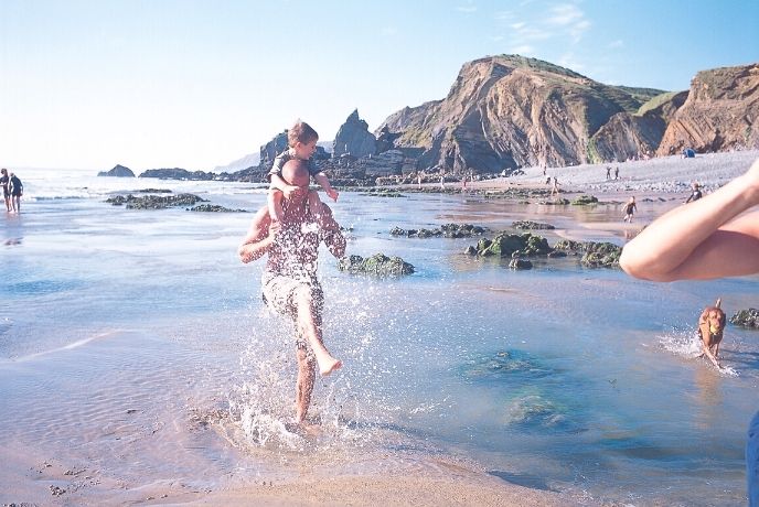 A family and their dog splashing around in the sea at Sandymouth Beach