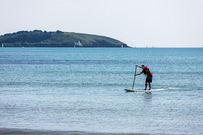 Someone paddleboarding at Swanpool beach in Falmouth