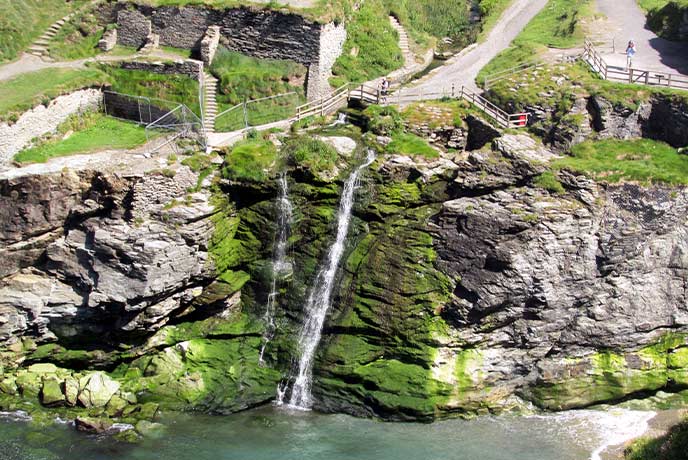 A waterfall flowing over the cliffs at Tintagel Haven in Cornwall