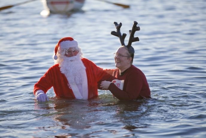 a man dressed as santa a woman dressed as a reindeer in the sea on christmas day
