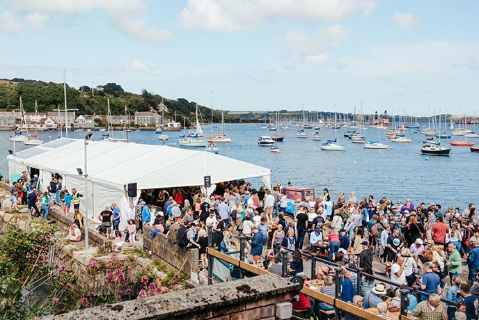 A crowd in front of the stage at the Falmouth International Sea Shanty Festival with Falmouth harbour in the background