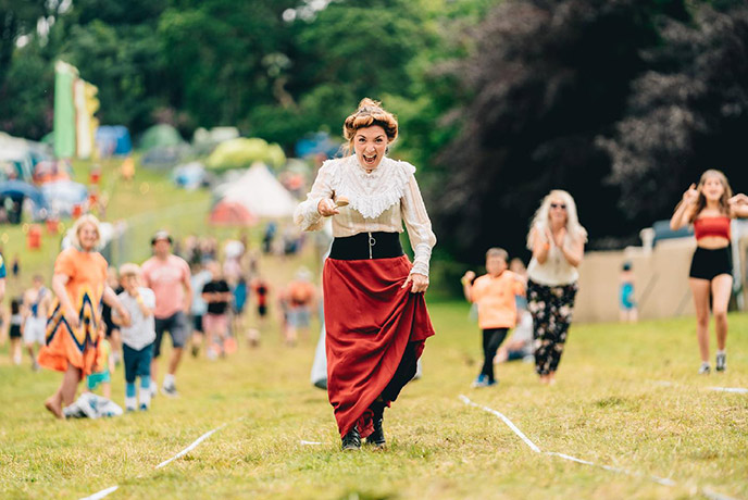Someone dressed in Victorian dress racing in the egg and spoon race at the Great Estate festival