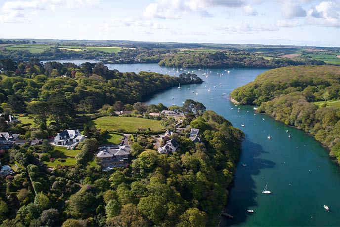The winding river around Helford in Cornwall, with houses in between the trees