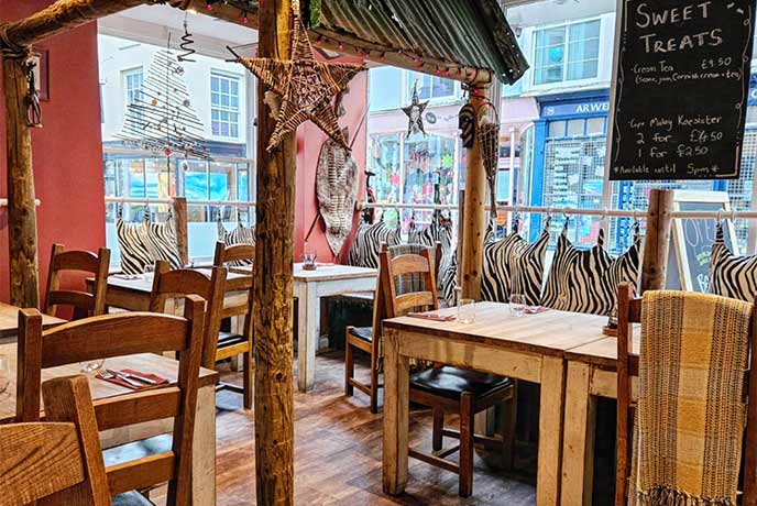 The wooden interior of Amanzi in Falmouth, with African decor and wooden tables