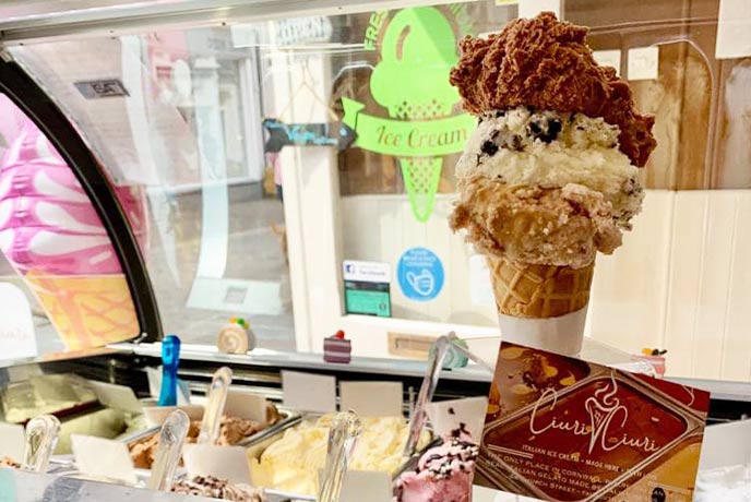 An ice cream cone in front of a counter full of ice cream at Ciuri Ciuri in Falmouth