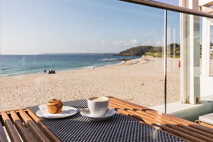 A coffee and a pastry overlooking the beach at Gylly Beach Café in Falmouth