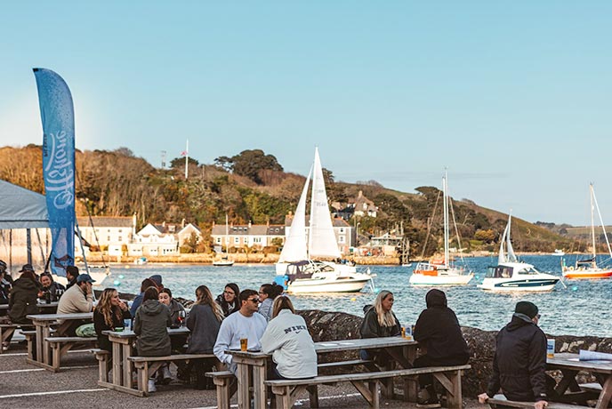 People sitting watching the Falmouth harbour in the pub garden of The Working Boat