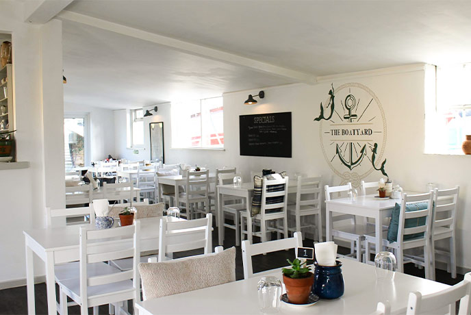 The bright and white interior of The Boatyard Café with lots of tables and chairs