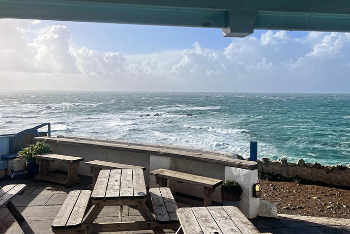 A wooden outdoor table overlooking the sea at Wavecrest on the Lizard Peninsula