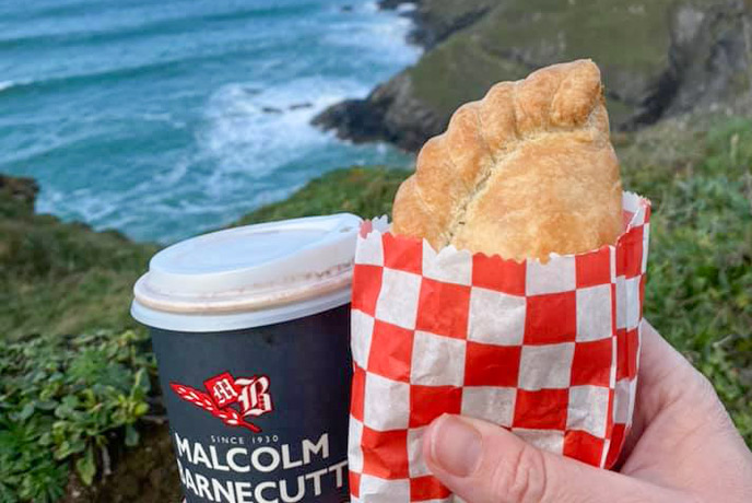 Someone holding a Cornish pasty from Malcom Barnecutt Bakery out on the cliffs