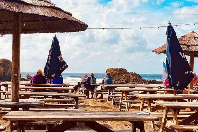Outdoor tables on the beach at The Watering Hole in Perranporth