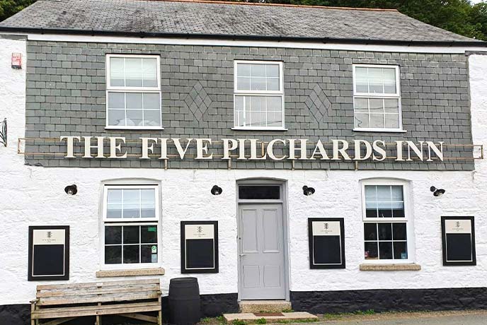 The white and grey stone exterior of The Five Pilchards Inn in Porthallow on the Lizard Peninsula