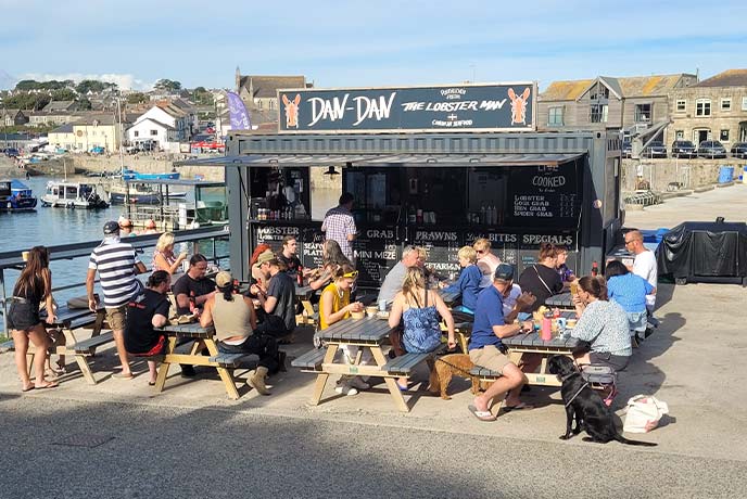 People sitting outside by Dan Dan the Lobster Man's food truck in Cornwall