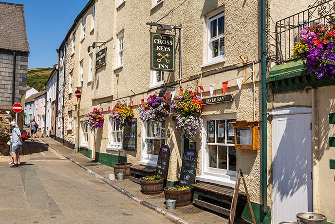 The traditional exterior of The Cross Keys in Cawsand, covered in hanging flowers