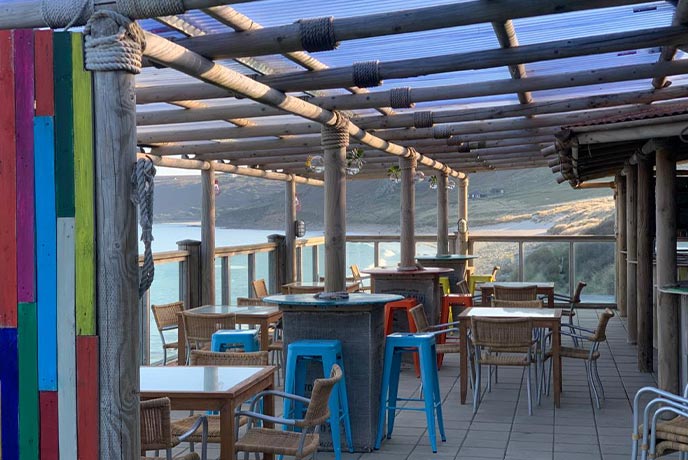 The colourful outdoor seating overlooking Sennen beach at Surf Beach Bar and Den