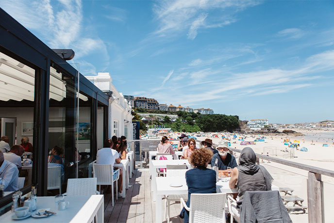 People eating outside on the terrace overlooking the beach at Porthminster Café