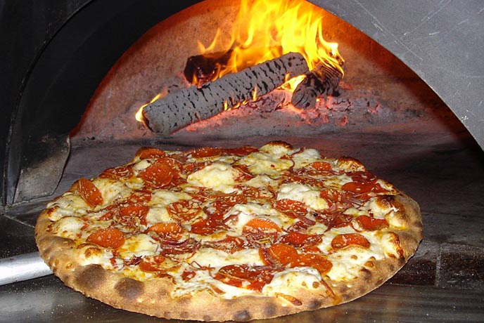 A pizza coming out of a wood fired oven at Roskilly's