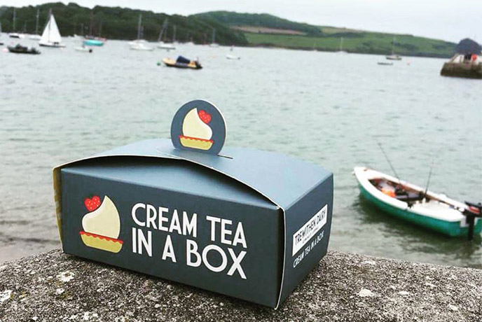 A cream tea in a box balancing on the harbour in St Mawes