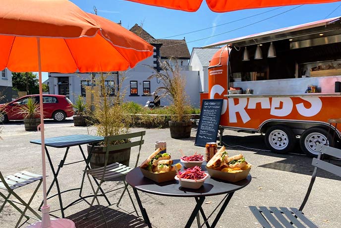 The bright orange food truck of Got Crabs with outdoor seating in Cornwall