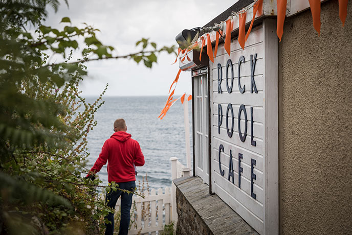 Someone walking down a path next to the Rock Pool Cafe sign