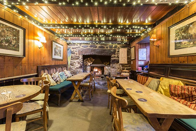 The cosy wood-lined room at Tinners Arms in Zennor where a fireplace is lit and fairy lights hang from the ceilings