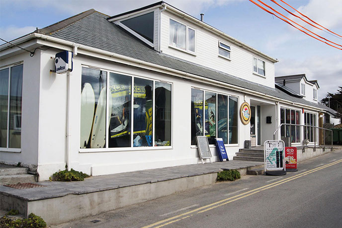 The white exterior of Trevone Beach Stores and Cafe with surf boards in the window