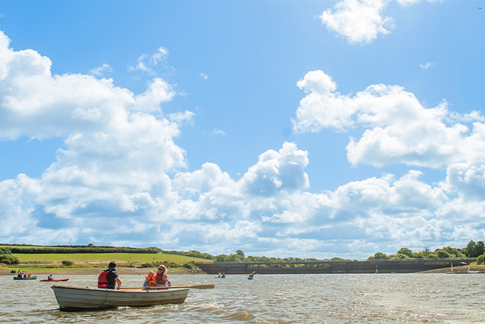 People rowing a boat across Tamar Lake in Cornwall