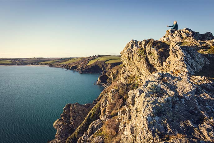 Someone sitting on top of the rocks at Nare Head on the Roseland Peninsula