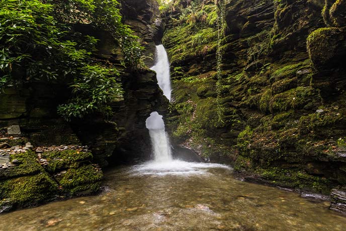 The mossy cliff and falling waterfall at St Nectan's Glen in Cornwall