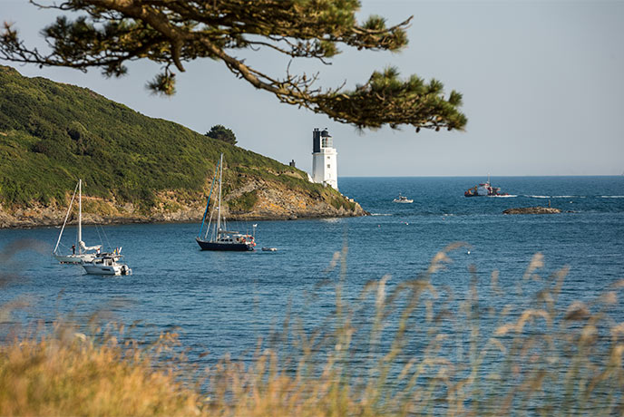 Boats sit in the water in front of St Anthony's Lighthouse on the Roseland Peninsula