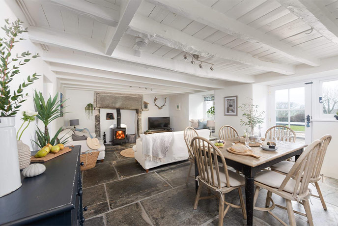 A cosy living room with a wood burner and slate floors at Bokelly Cottage in Cornwall