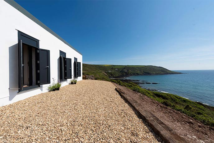 The white exterior of Captain Blake's Retreat looking out over the cliffs at the Cornish seas