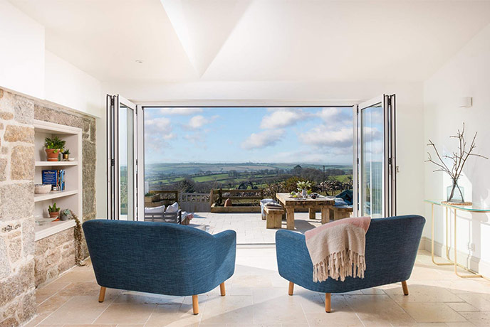 Two large chair facing out through open bi-fold doors at the terrace and countryside beyond