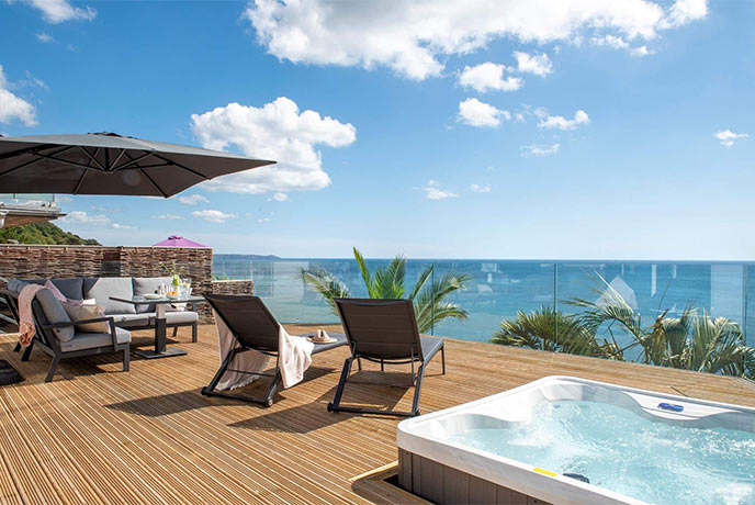The incredible wooden terrace at Ocean View, with sun loungers, a hot tub, and reaching sea views