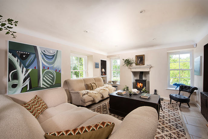 The pretty living room at Penfoye in Cornwall with a comfy sofas and a lit wood-burner